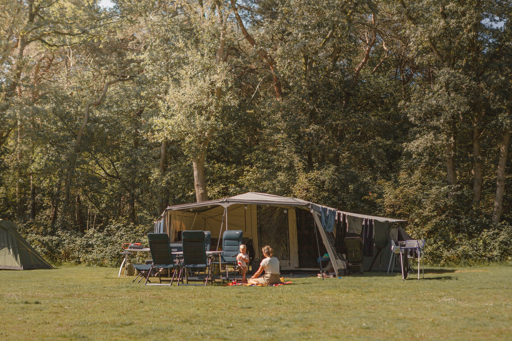 Moeder en kind voor de tent op kampeerveld Akker bij Lemeler Esch natuurcamping