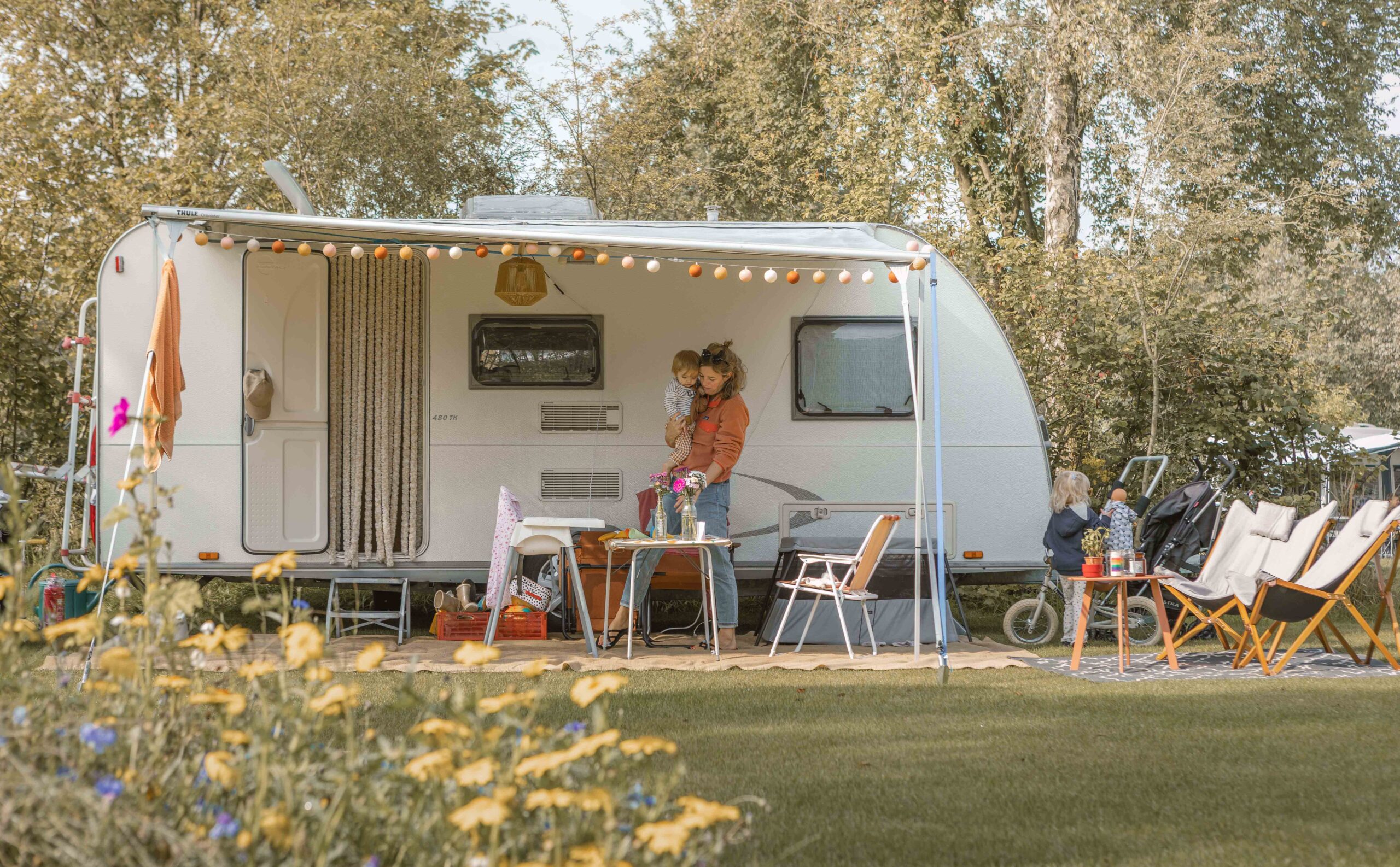 Moeder, peuter en baby voor de caravan op kampeerveld Boomgaard bij Lemeler Esch natuurcamping