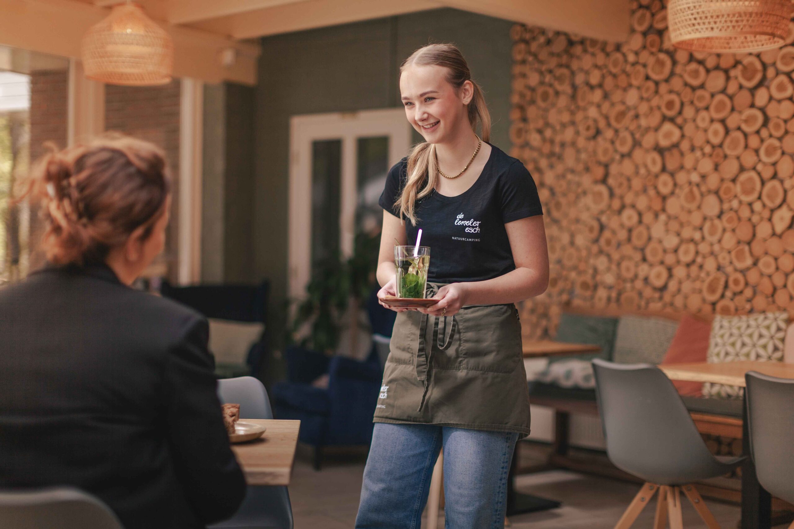 Collega in de serre van Boscafé Lemeler Esch met huisgemaakte taart en verse muntthee in haar hand