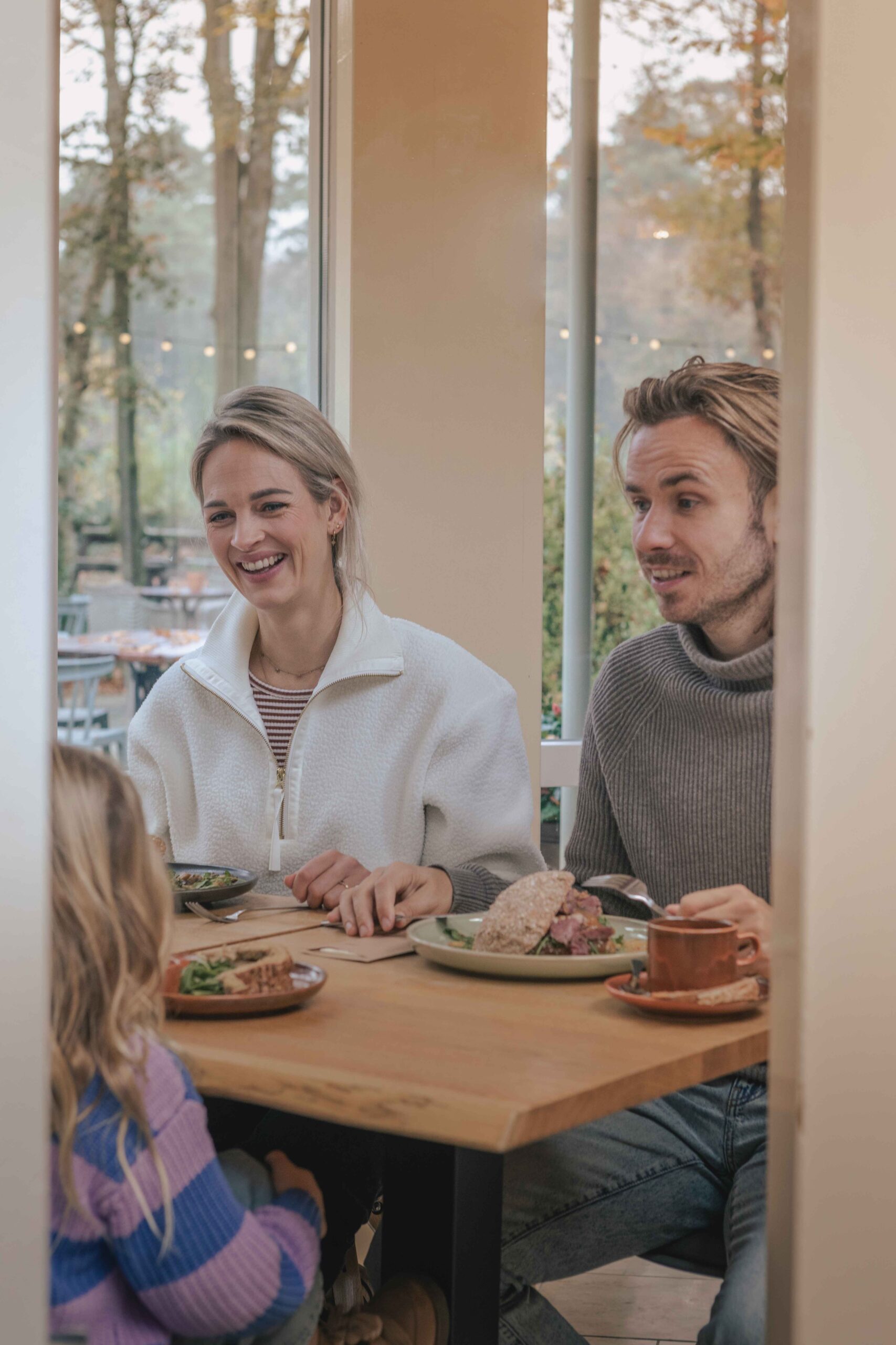 Jong gezin aan het lunchen in de serre van Boscafé Lemeler Esch